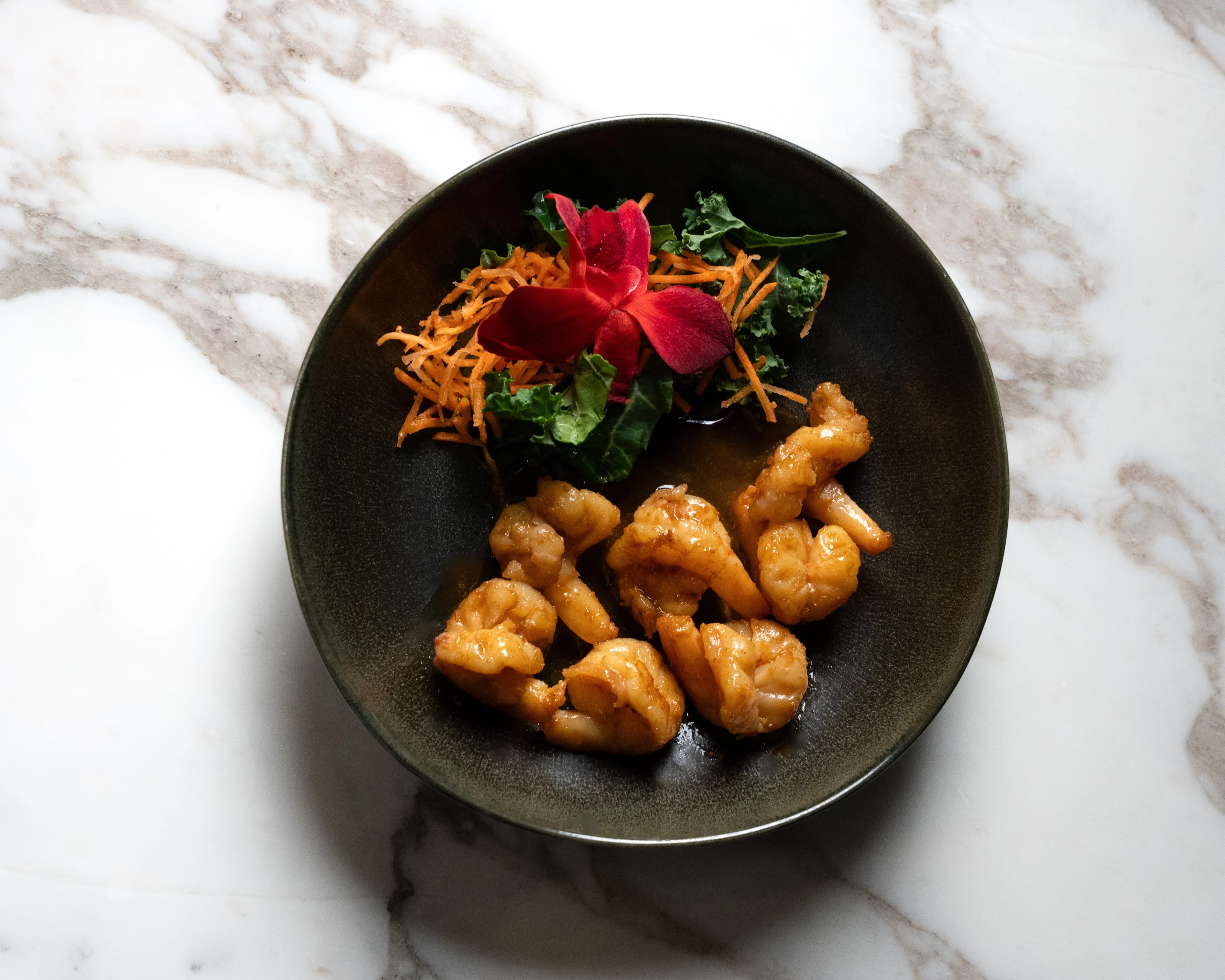 An overhead bowl of golden fried bites with a carrot-and-greens garnish at Sushi Sake.