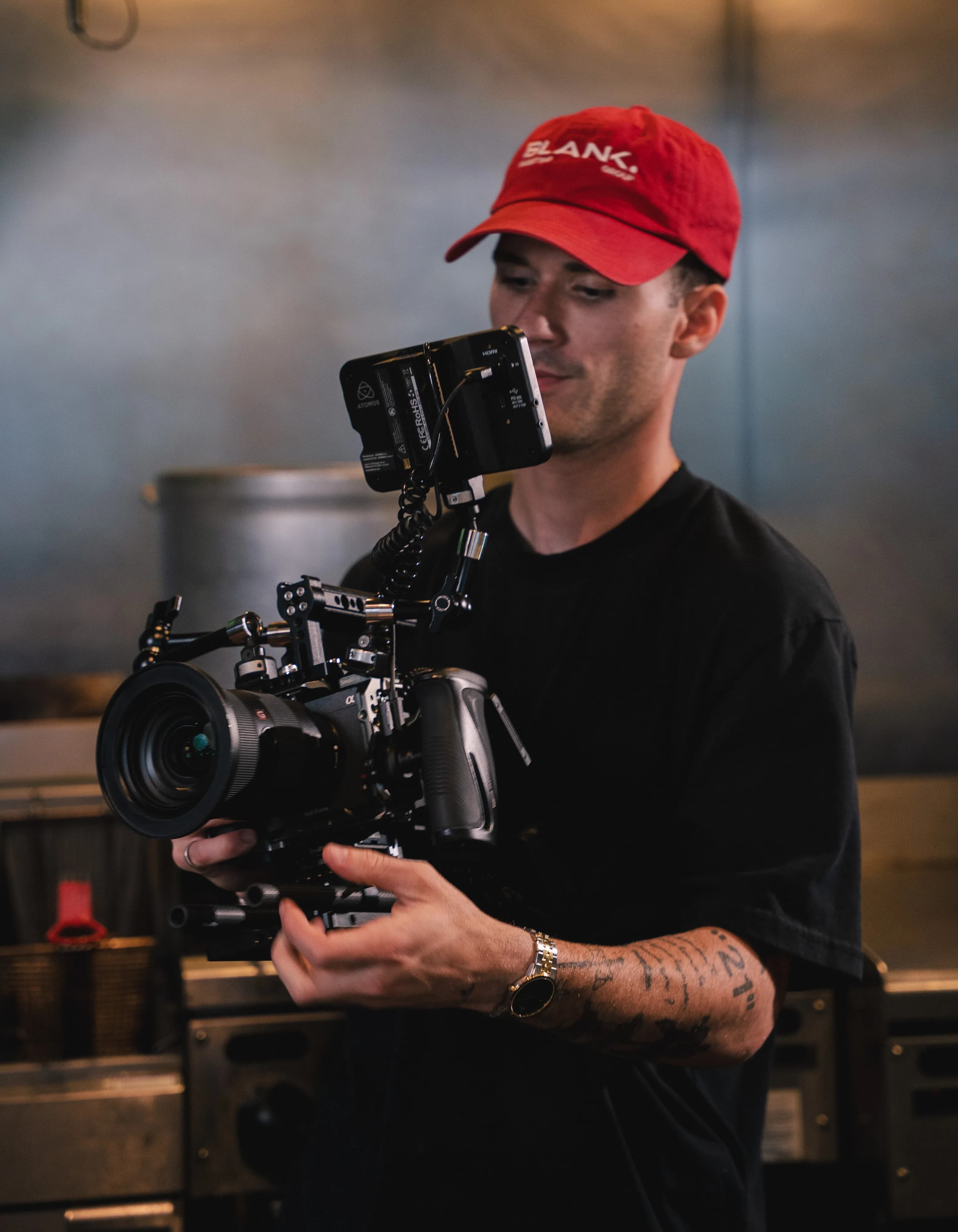 A Blank Marketing Group videographer in a red cap holds a cinema camera in the Sushi Sake kitchen.