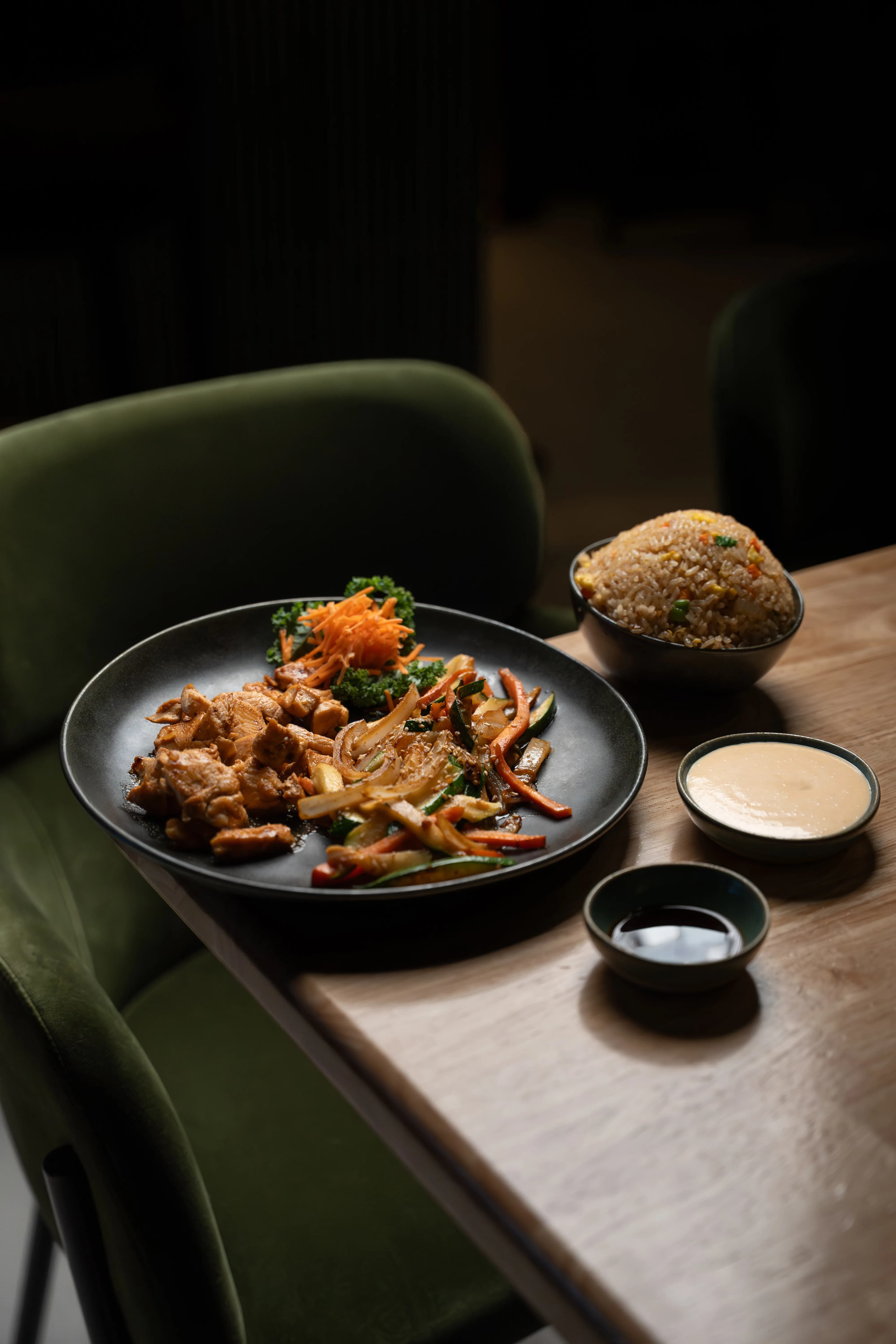 A moody plate of a fried Sushi Sake dish with dipping sauce against a green booth.